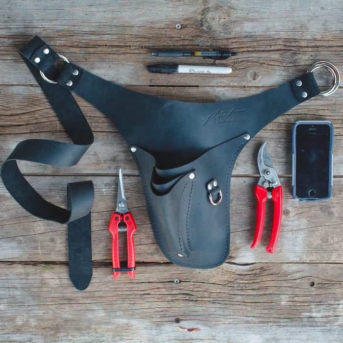 An overhead of Floret’s black right-handed tool belt, pens, snips, pruners, cell phone