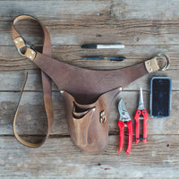 An overhead of Floret’s brown left-handed tool belt, pens, snips, pruners, cell phone